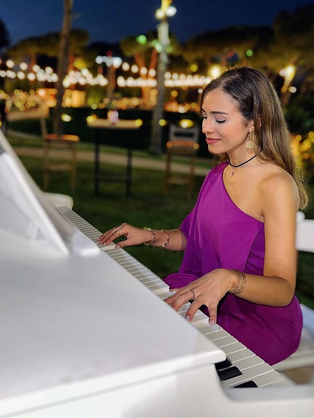 Mayssa playing the piano at an evening event